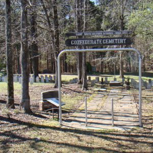 Cemetery behind gate and sign with rope fence with trees