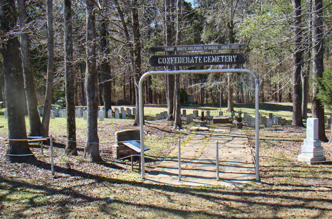 Cemetery behind gate and sign with rope fence with trees