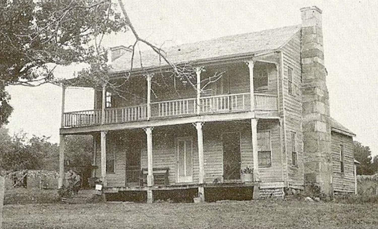 Two-story house with covered porch and balcony and stone chimney