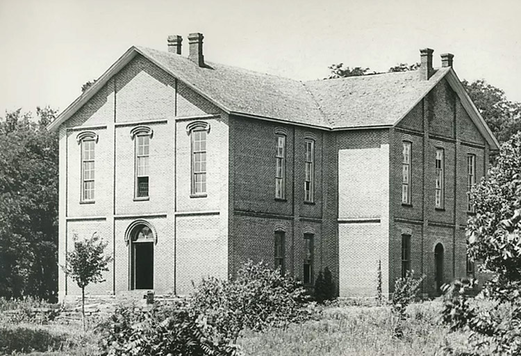 Two-story brick building with chimneys and arched doorways