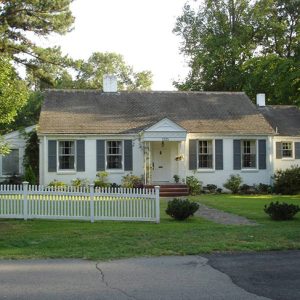 Single-story house with white fence on street