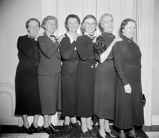 Six white women in dresses posing in line