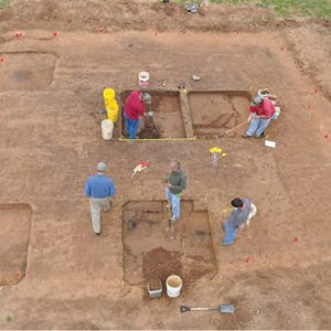 Group of white archaeologists excavating a site as seen from above