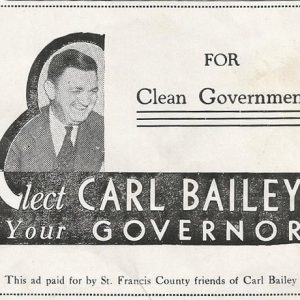 White man smiling in suit and tie with campaign logo and text