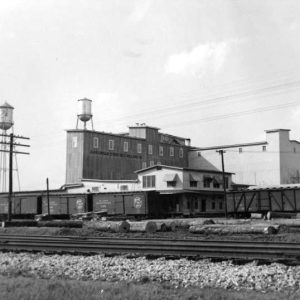 Multistory industrial buildings with water towers and railroad tracks in the foreground