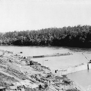 River with dam under construction and trees in background
