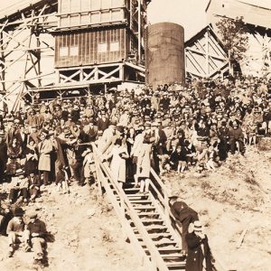 Crowd of white people gathered with stairs tower and raised tracks