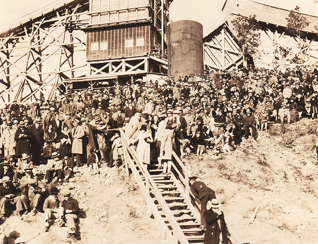 Crowd of white people gathered with stairs tower and raised tracks