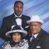Two African-American men in suits and woman in hat and dress
