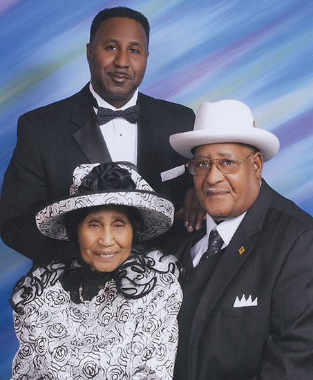 Two African-American men in suits and woman in hat and dress