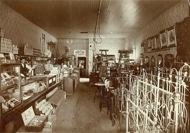 Interior of general store with white man and woman and items in display cases
