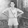 Young white man in tank top with Olympic logo and shorts with his hands on his hips