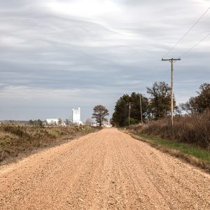 Dirt road leading to horizon with silo in background