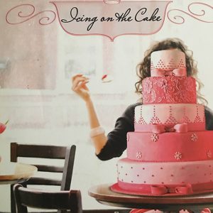 White woman sitting behind multi-tier wedding cake under "Icing on the Cake" title on book cover