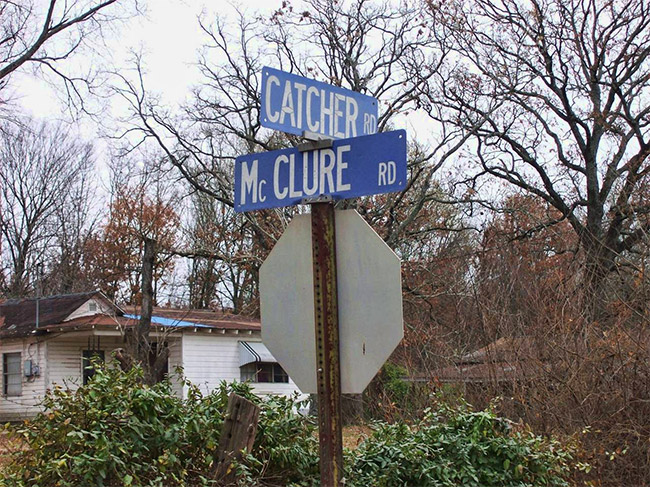 street signs marking the intersection of Catcher and McClure roads in front of house