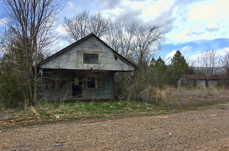 Abandoned building and outbuilding on dirt road