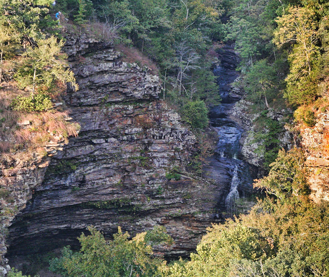 elevated distant view of waterfall and striated rock face, trees