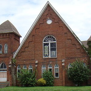 Brick church building with A-frame roof and bell tower