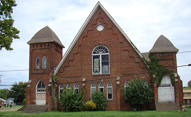 Brick church building with A-frame roof and bell tower