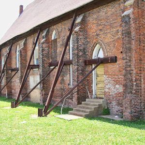 Dilapidated brick church building with metal braces supporting the sides