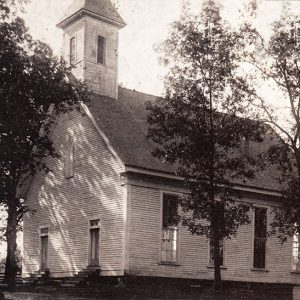 Single-story church building with cupola and two front doors with steps