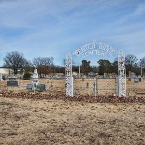 Closed cemetery gates with white metal arch entrance and fence