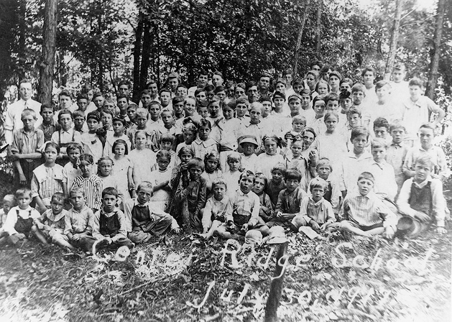 Group of white children and teachers with trees in the background