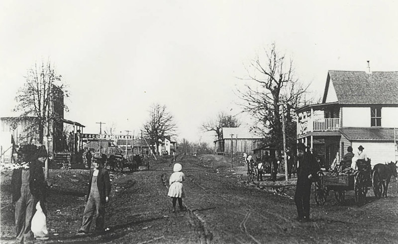 Men child and horse drawn wagons on dirt street in town