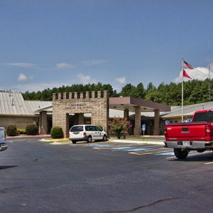 Single-story building with covered entrance on parking lot with flag pole
