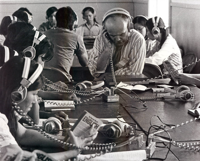 Vietnamese men and women seated at tables listening to instructional material