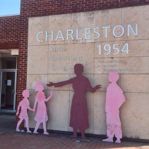 Single-story brick building with "Charleston 1954" on its side with silhouettes of woman and children