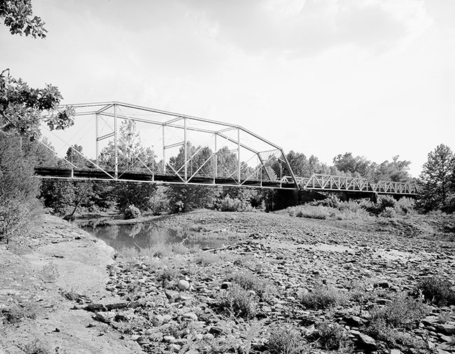 Steel arch truss bridge over nearly dry creek bed