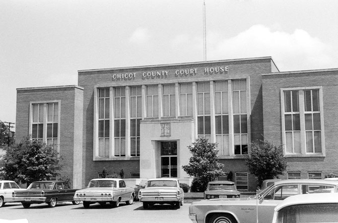 Multiple-story building with "Chicot County Court House" above the entrance and cars in the parking lot