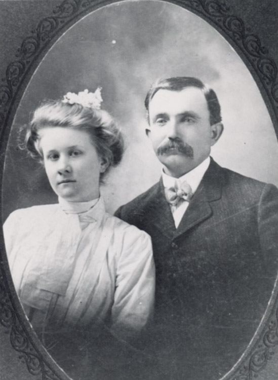 White man with mustache in suit and bow tie with white woman in dress