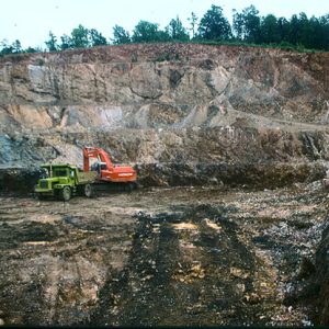 Green dump truck and red excavator in open pit mine