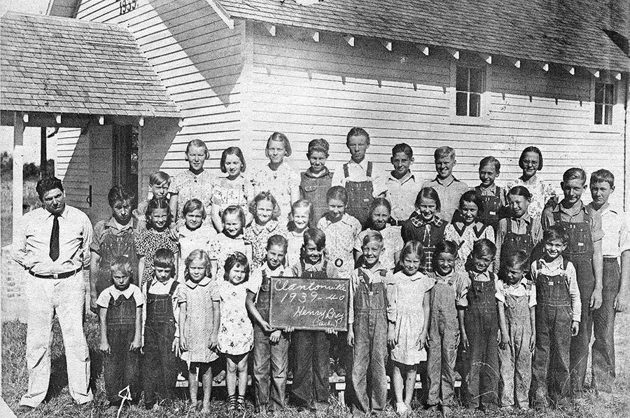 White children and teachers outside school house