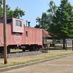 Red "Missouri Pacific Lines" train car on display with sign and pavilion with trees