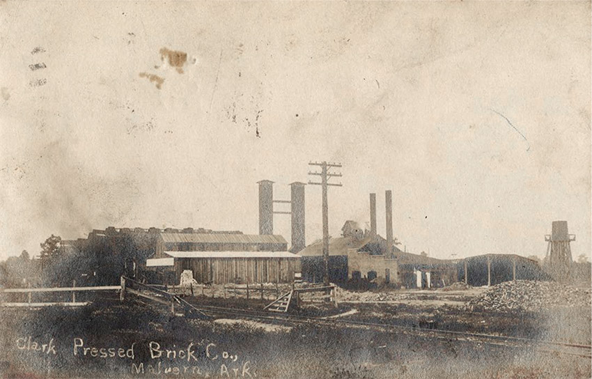 Factory buildings with smoke stacks and railroad tracks in the foreground