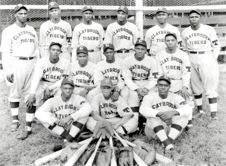 African-American men in uniforms labeled "Claybrook Tigers" pose for a group photograph with bats and gloves laid out in front of them