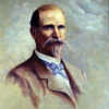 White man with handlebar mustache and beard in suit and blue bow tie