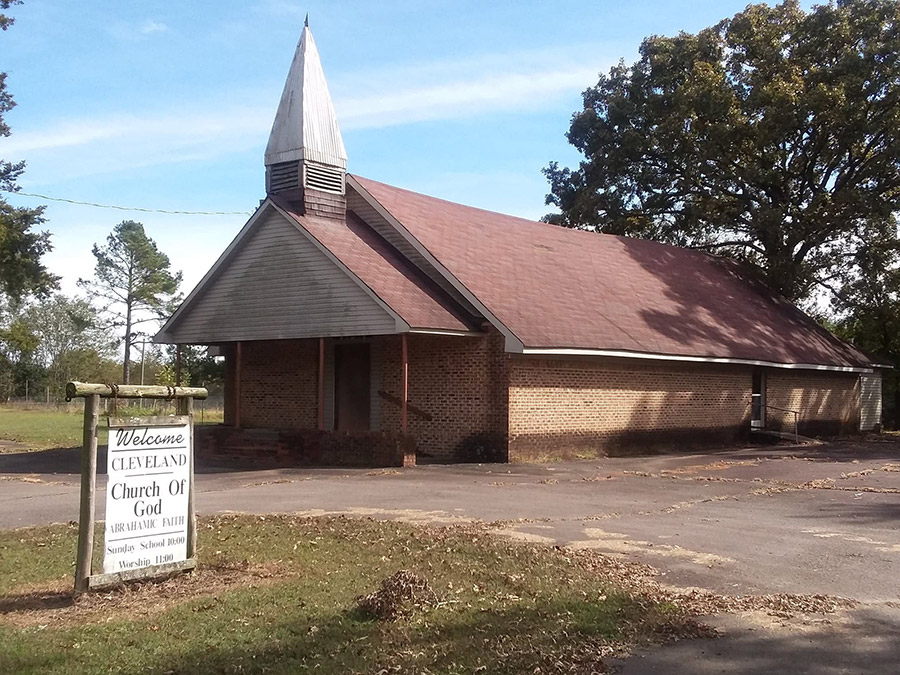 Brick church building with steeple and sign on parking lot