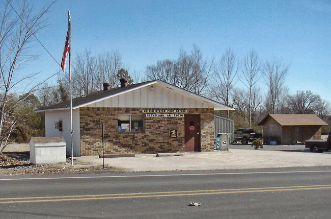 Brick building with flag pole and American flag as seen from across paved road