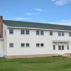 Multistory building with covered porch and white siding on grass