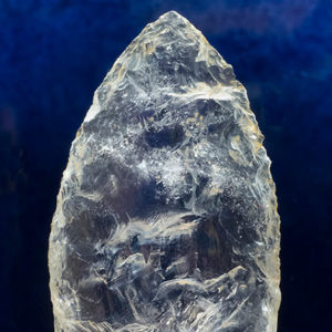Close-up of crystal arrowhead point on blue background