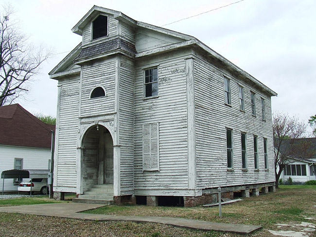 Two-story clapboard church with arched entrance somewhat dilapidated