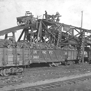 Train cars being machine-loaded with coal