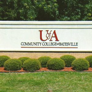 "U of A Community College at Batesville" sign with brick foundation in flower bed with small round bushes in it