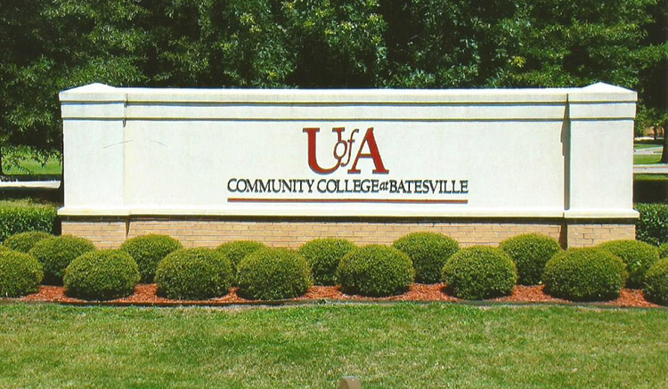 "U of A Community College at Batesville" sign with brick foundation in flower bed with small round bushes in it