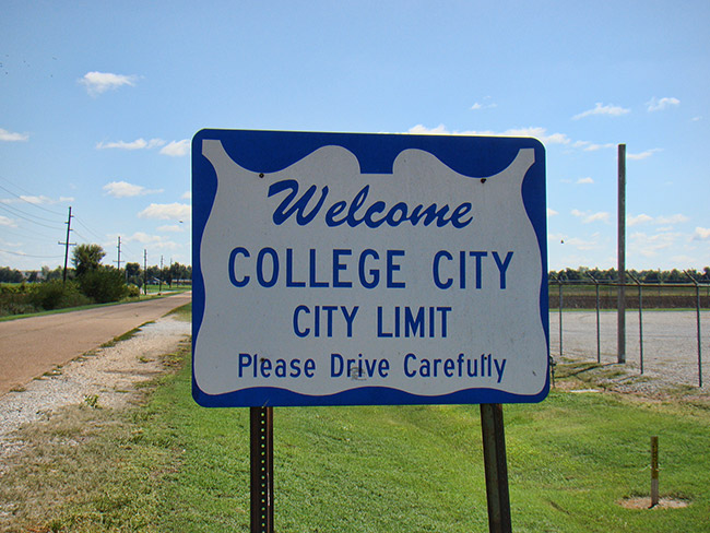 Blue and white "Welcome College City city limit" sign