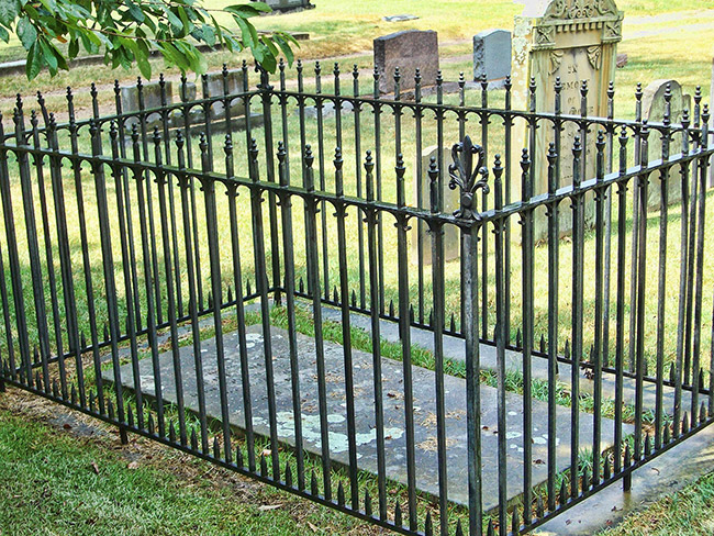 Iron fence around engraved grave ledger in cemetery